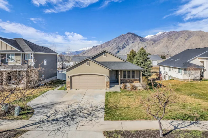 View of front of home featuring driveway, a mountain view, a garage, a porch, and a front yard