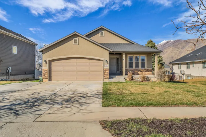 View of front of property with stucco siding, an attached garage, driveway, a front yard, and a porch