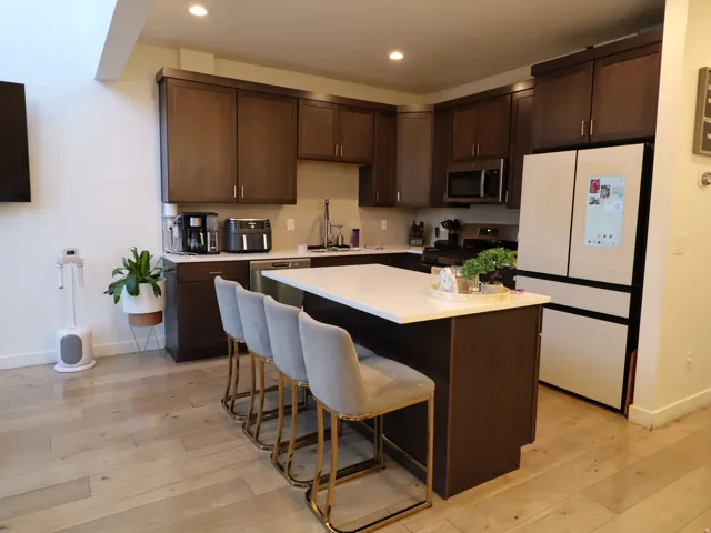 Kitchen featuring dark wood finish cabinets, stainless steel appliances, a breakfast bar, light wood-type flooring, and recessed lighting