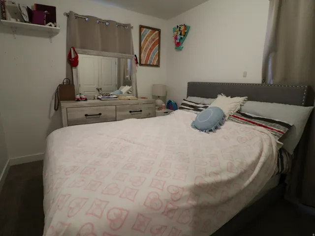 Bedroom with baseboards and dark colored carpet