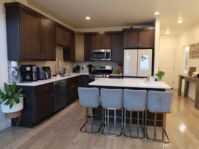 Kitchen with stainless steel appliances, a center island, light wood-style floors, dark wood finish cabinets, and recessed lighting