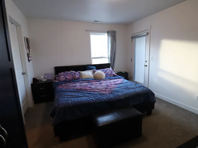 Bedroom with dark colored carpet and baseboards