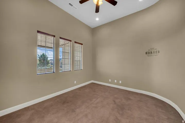 Carpeted spare room with ceiling fan, a high ceiling, and recessed lighting