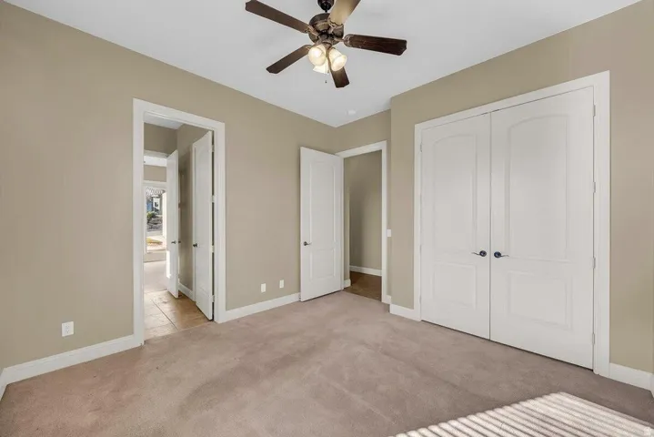 Unfurnished bedroom featuring light carpet, ceiling fan, and a closet