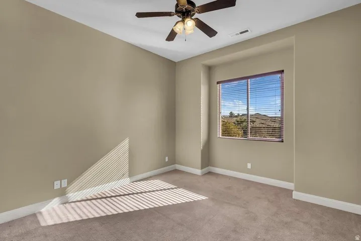Unfurnished room featuring light carpet and a ceiling fan