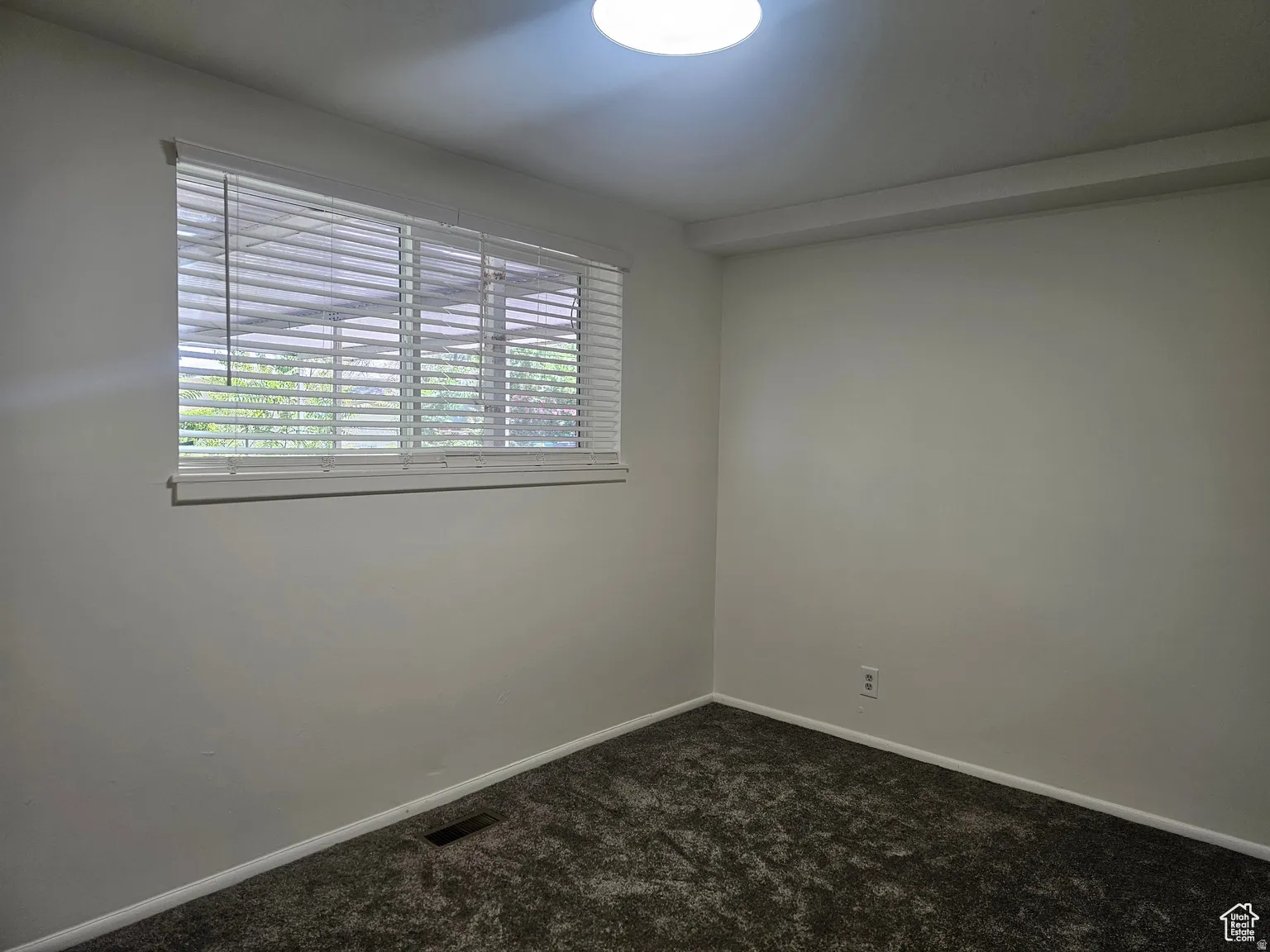 Spare room featuring dark carpet and baseboards