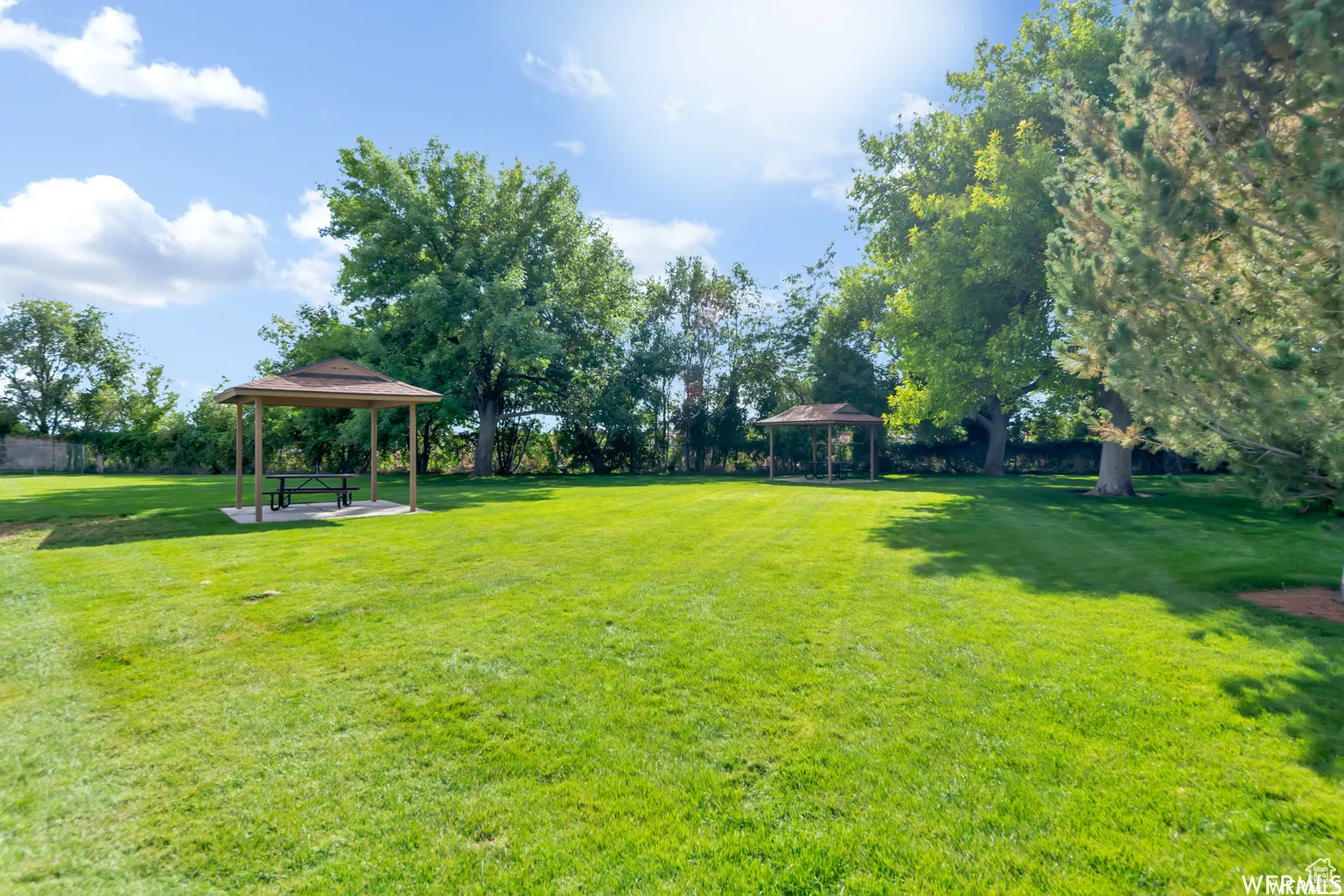 View of grassy yard with a gazebo and a patio area