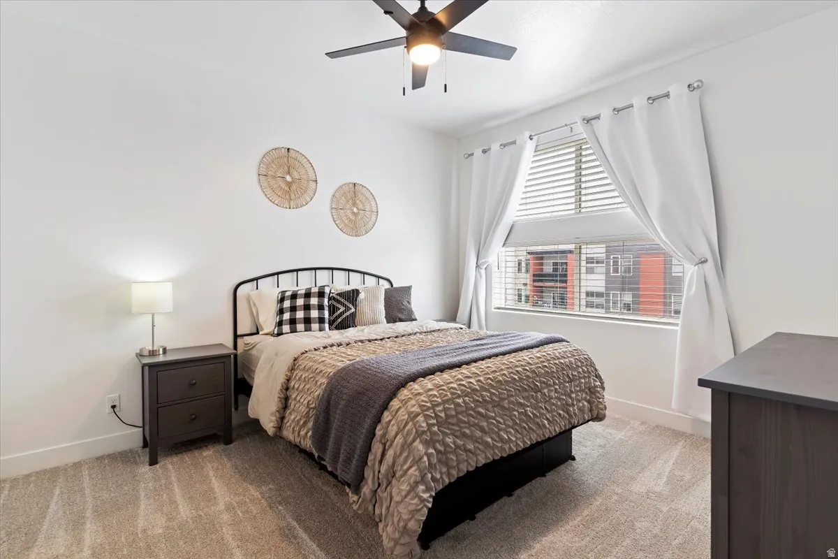 Bedroom with light carpet and a ceiling fan
