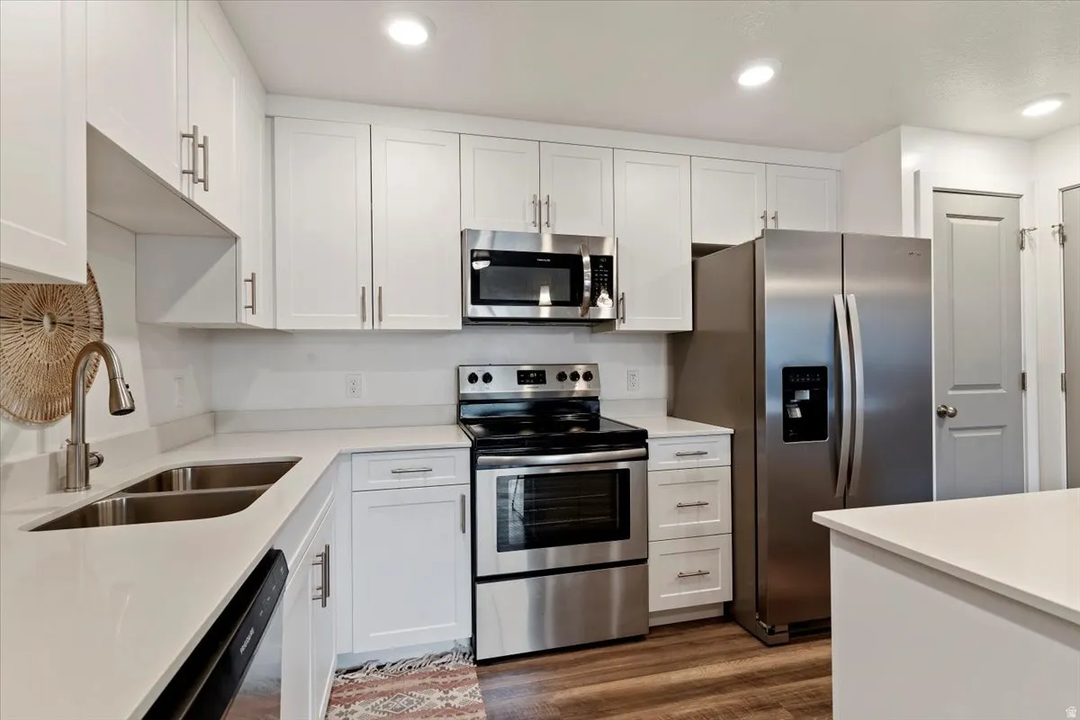Kitchen featuring stainless steel appliances, white cabinets, dark wood-style flooring, and recessed lighting