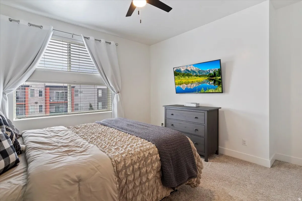Bedroom with light carpet and a ceiling fan
