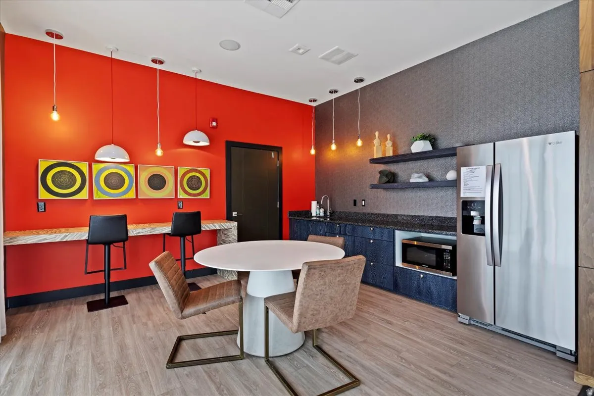 Kitchen featuring stainless steel appliances, open shelves, dark stone counters, and decorative light fixtures