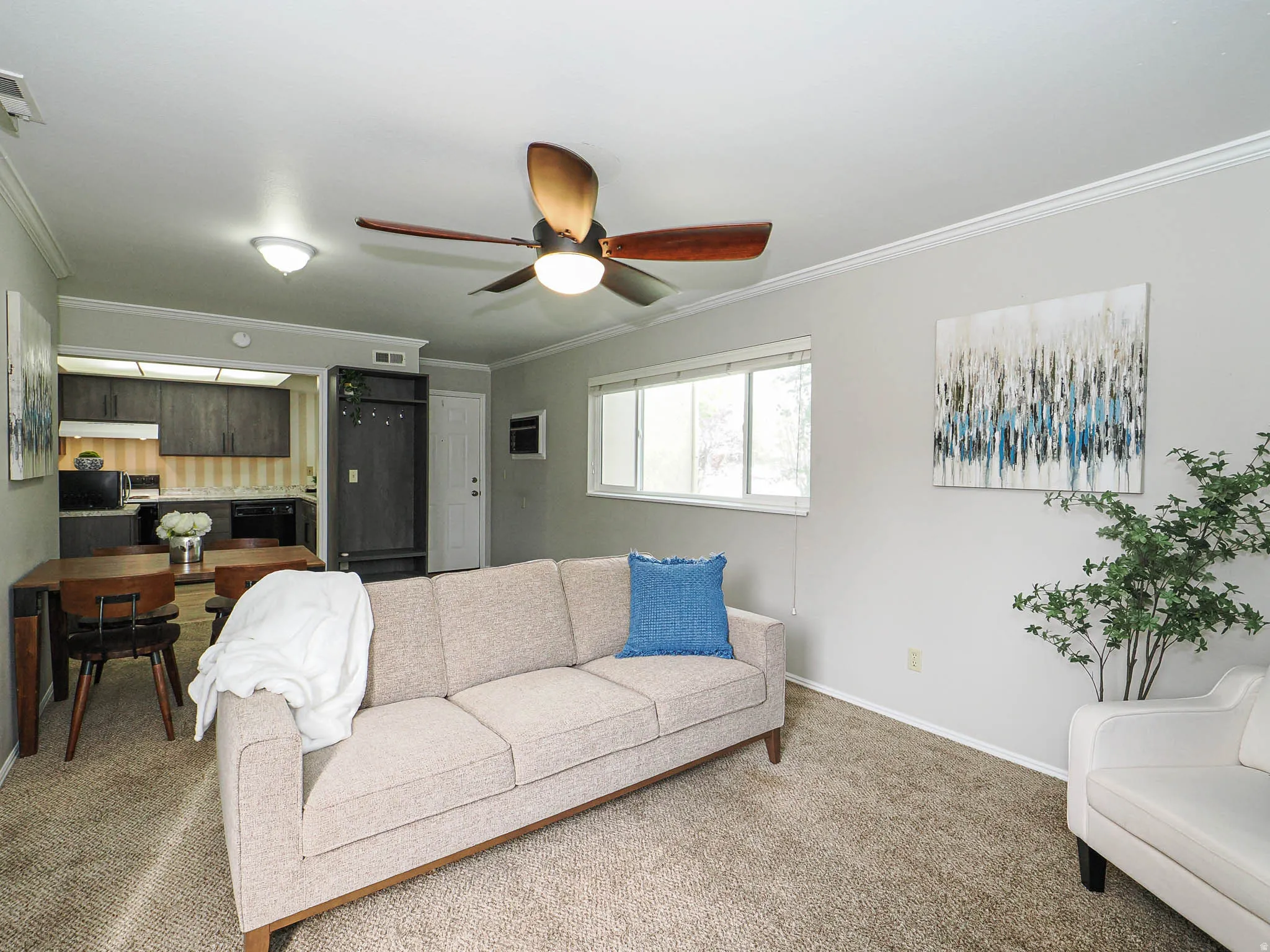 Living room with carpet floors, crown molding, and ceiling fan