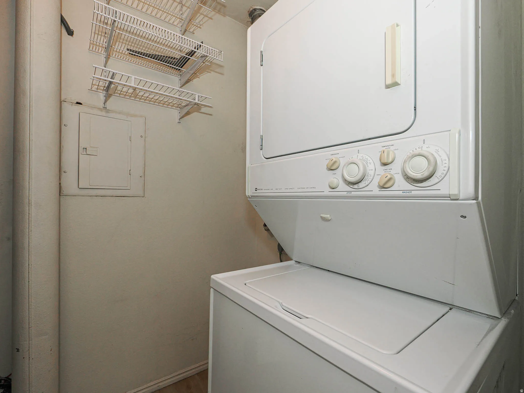 Laundry area featuring stacked washer and dryer and electric panel