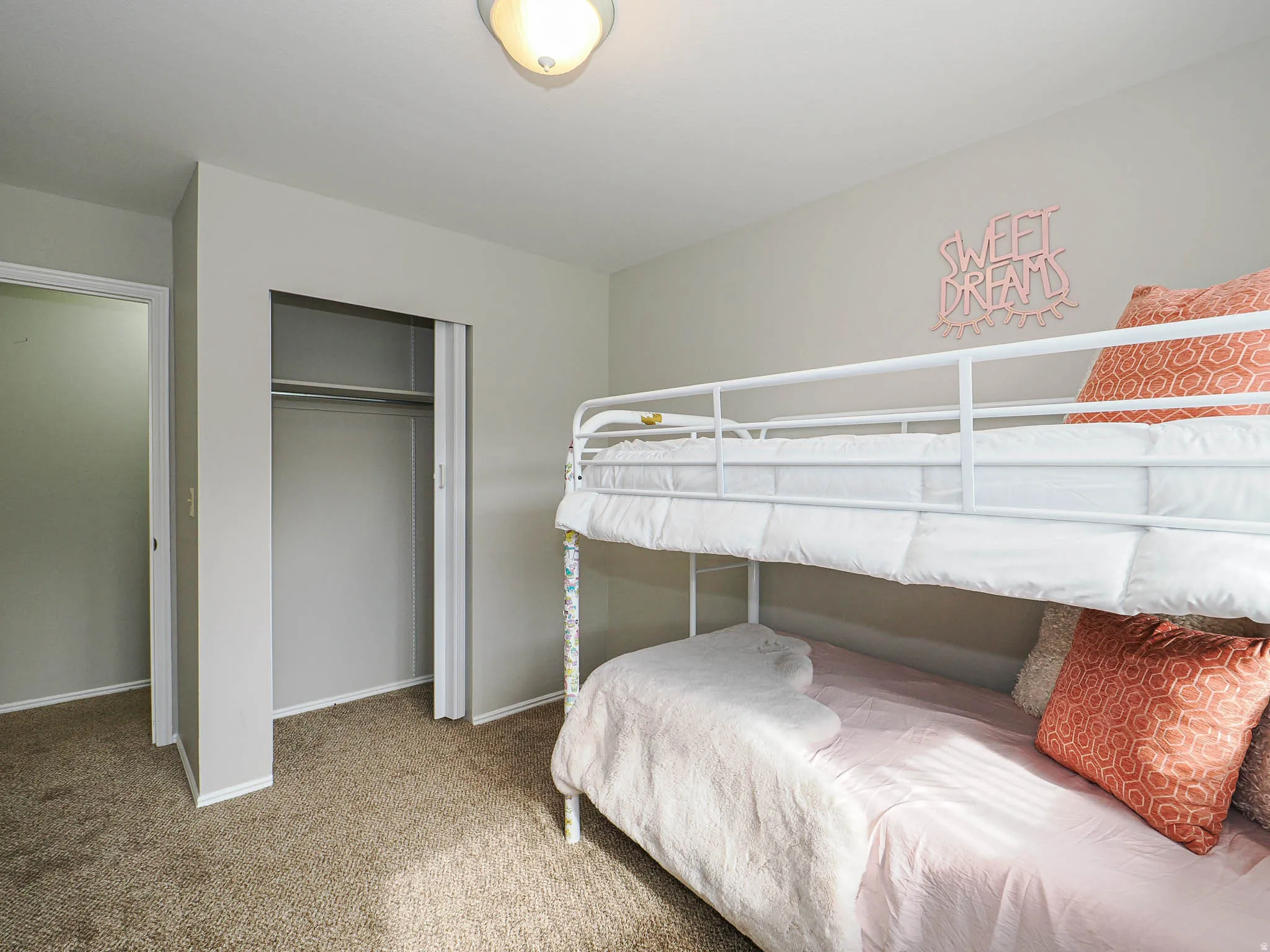 Bedroom with light carpet and a closet