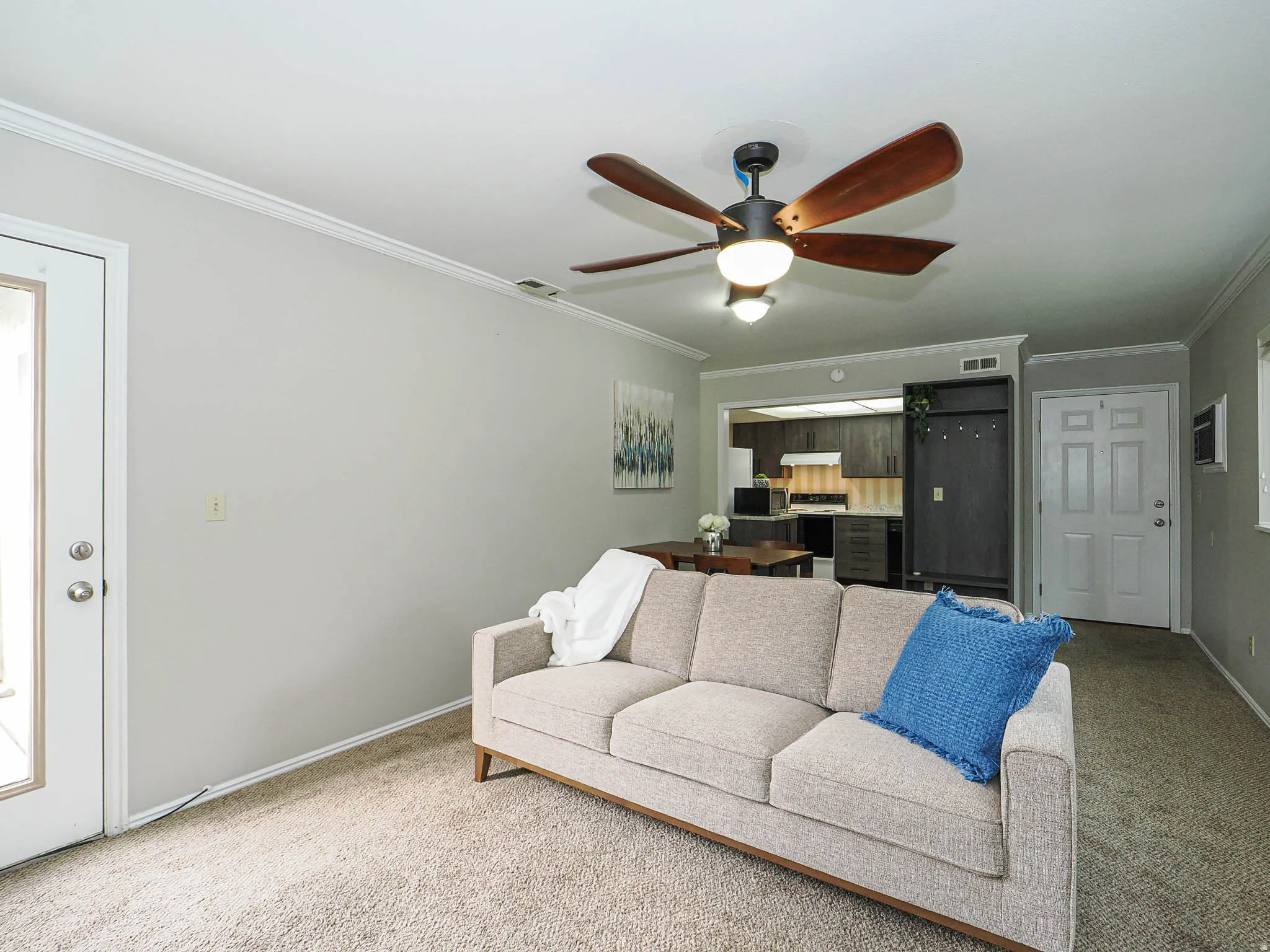 Living room with light colored carpet, ceiling fan, and ornamental molding