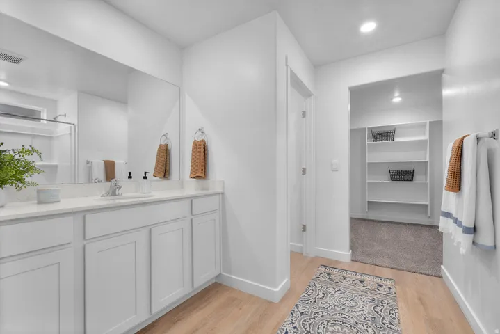 Bathroom featuring recessed lighting, vanity, light wood-style flooring, and a spacious closet