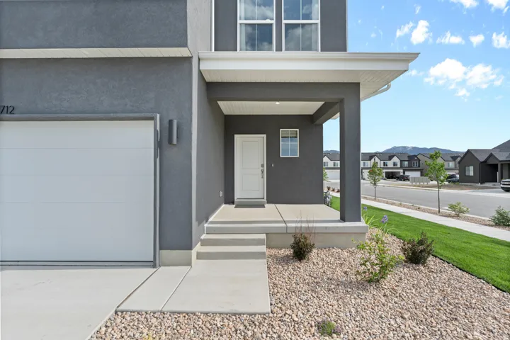 Property entrance with covered porch, a residential view, stucco siding, and a garage