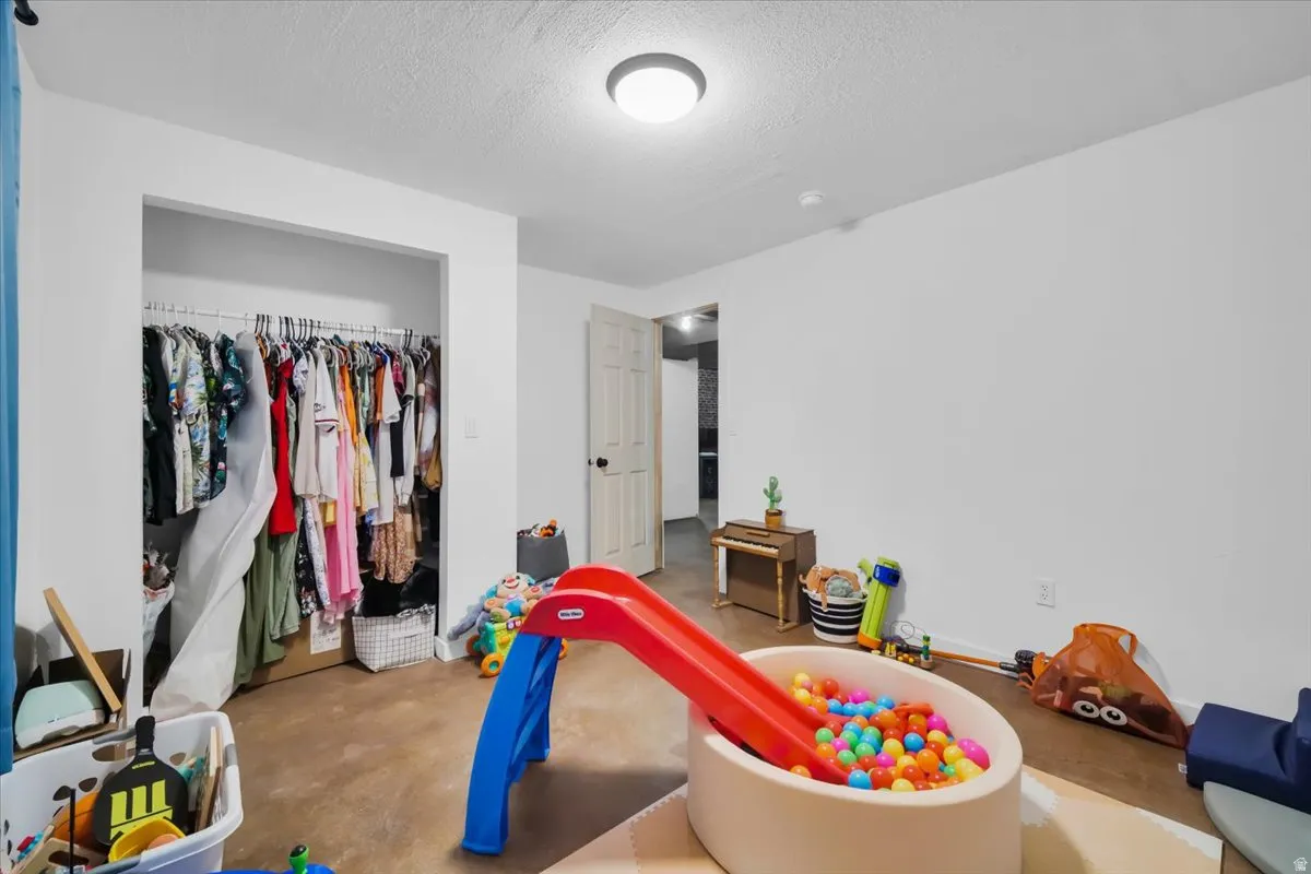 Rec room with a textured ceiling and concrete floors