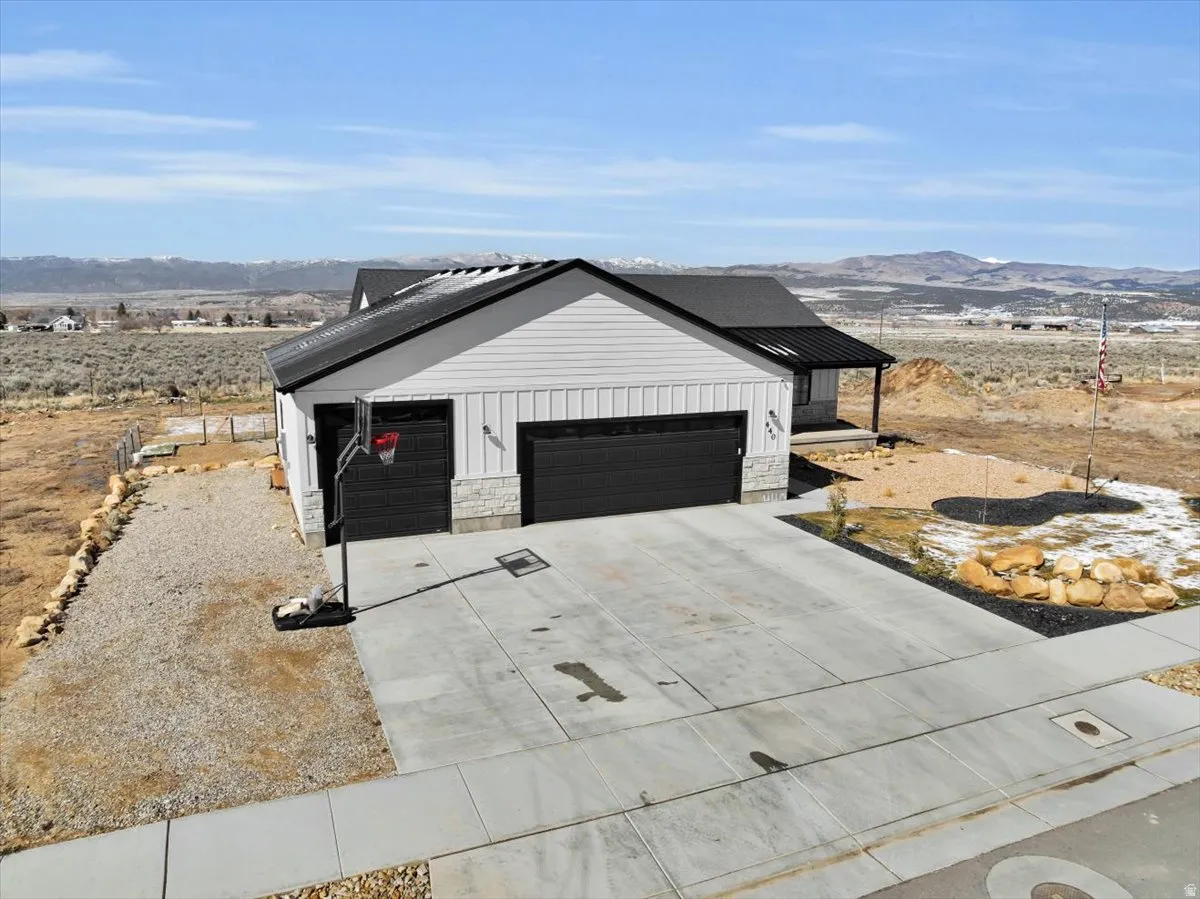Modern inspired farmhouse featuring a mountain view, concrete driveway, stone siding, and a garage