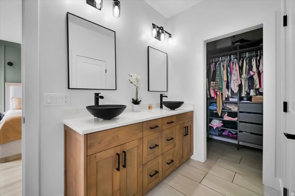 Full bath with double vanity, a walk in closet, and ensuite bathroom