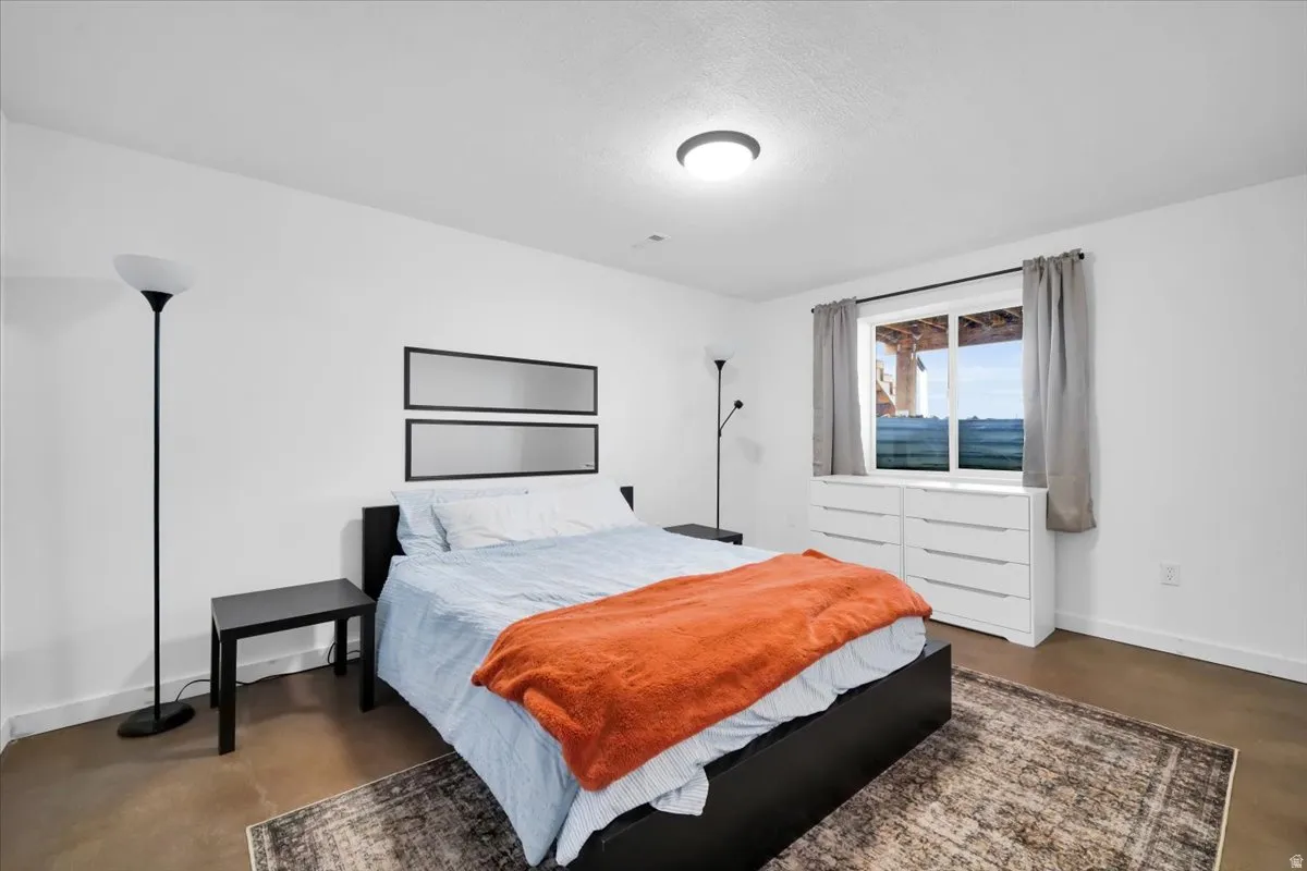Bedroom featuring baseboards and finished concrete flooring