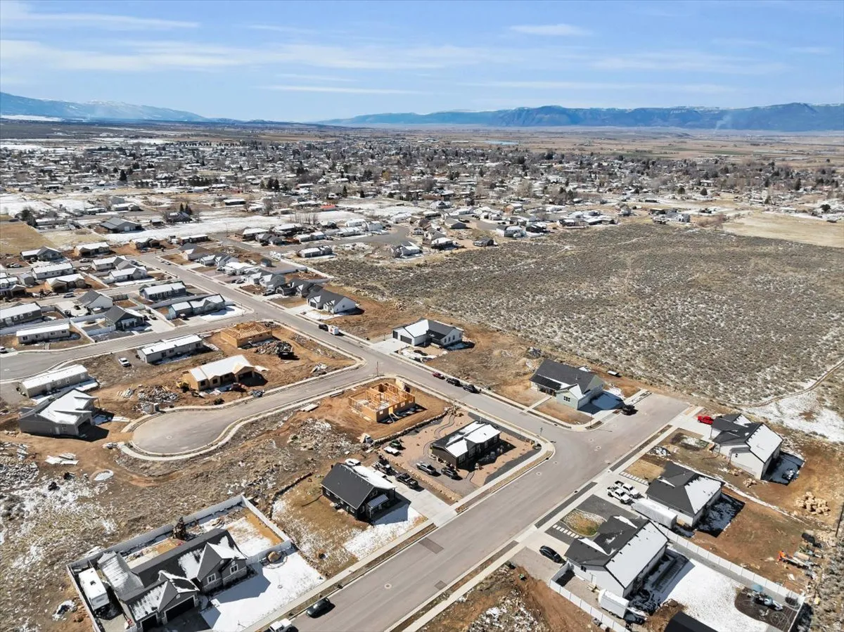 Aerial view of property and surrounding area featuring nearby suburban area and a mountainous background