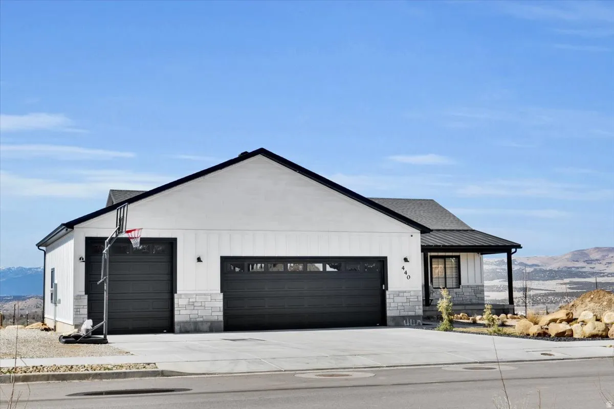 Modern inspired farmhouse featuring a mountain view, stone siding, an attached garage, and concrete driveway