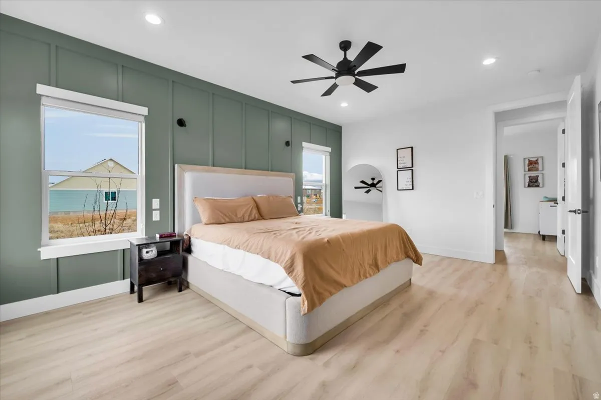 Bedroom with a decorative wall, light wood-type flooring, recessed lighting, and ceiling fan