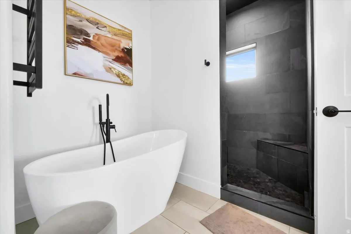 Bathroom with light tile patterned floors, a freestanding tub, and walk in shower