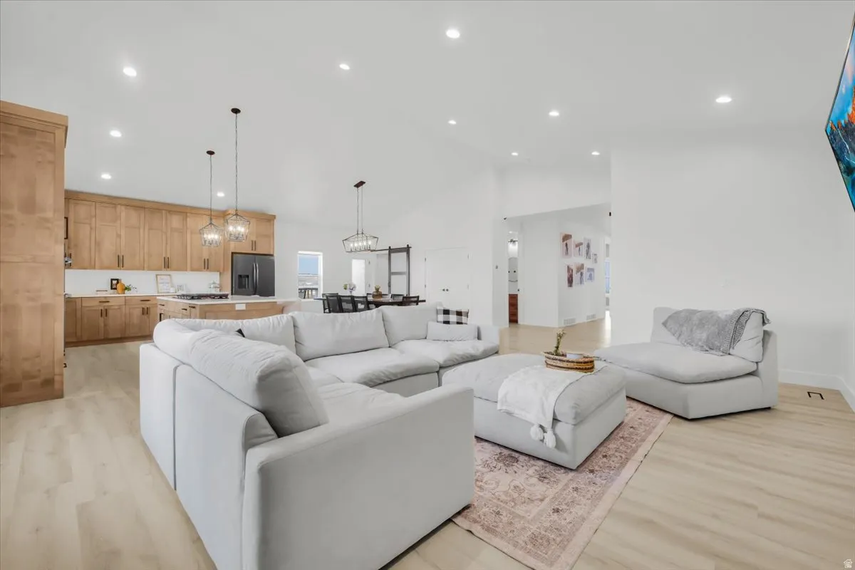 Living room featuring light wood-type flooring, lofted ceiling, and hanging lights