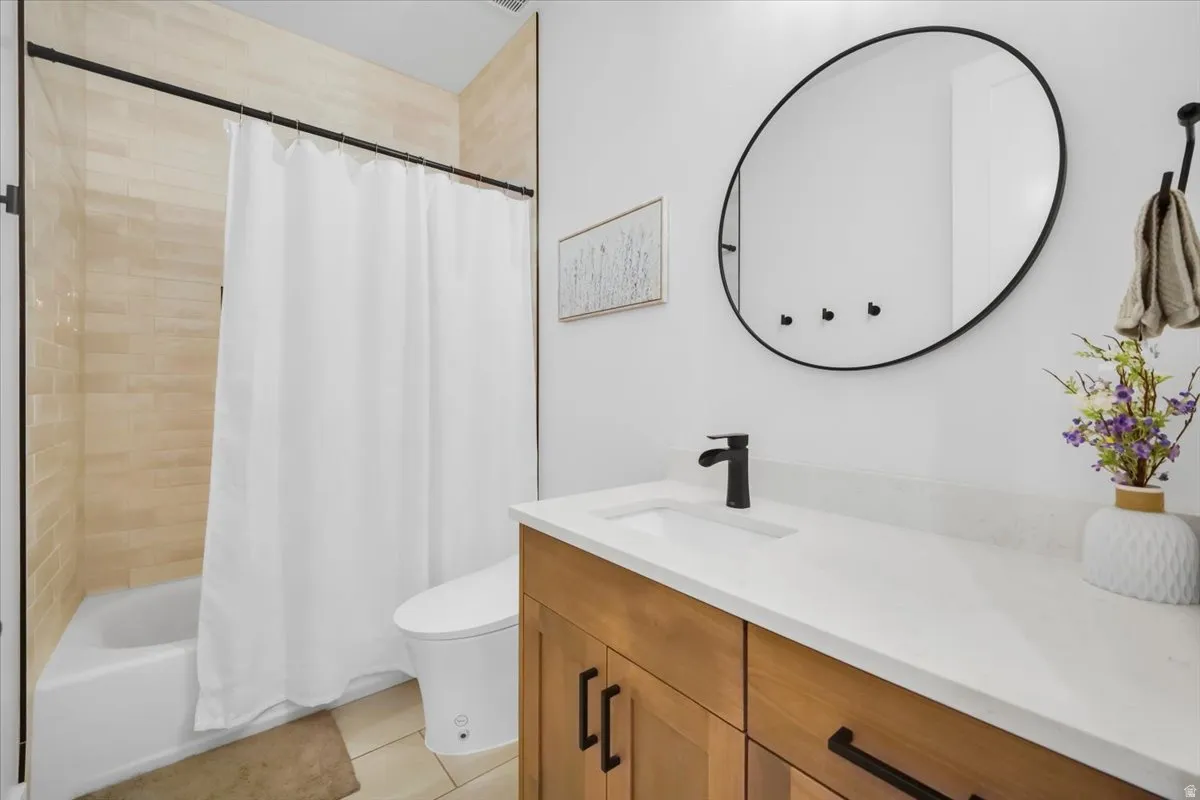 Bathroom featuring vanity, shower / bath combination with curtain, and light tile patterned floors