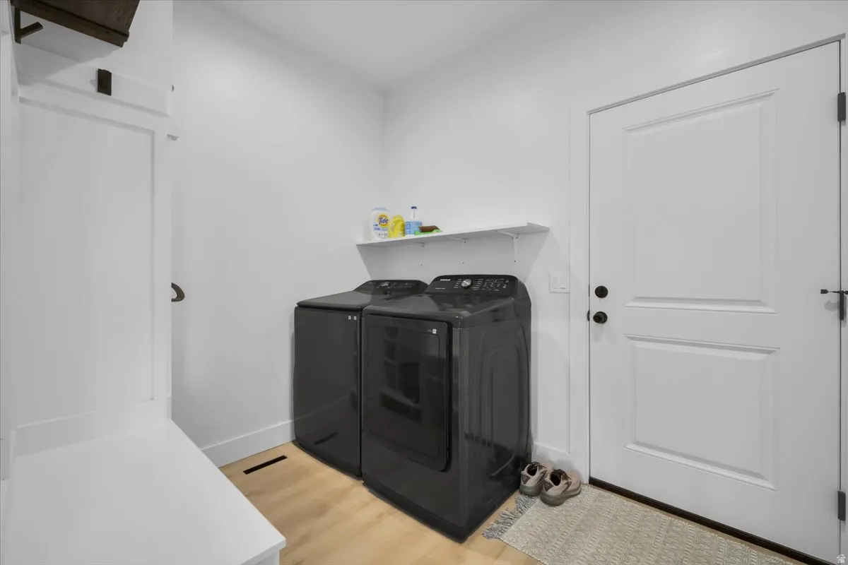 Laundry area featuring light wood-style flooring and washing machine and dryer