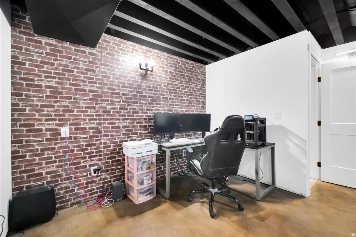 Office area with brick wall, finished concrete floors, and beam ceiling