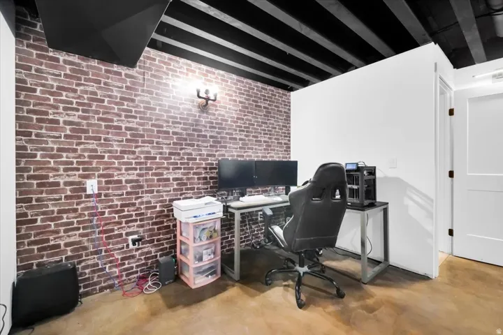 Office area with brick wall, finished concrete floors, and beam ceiling