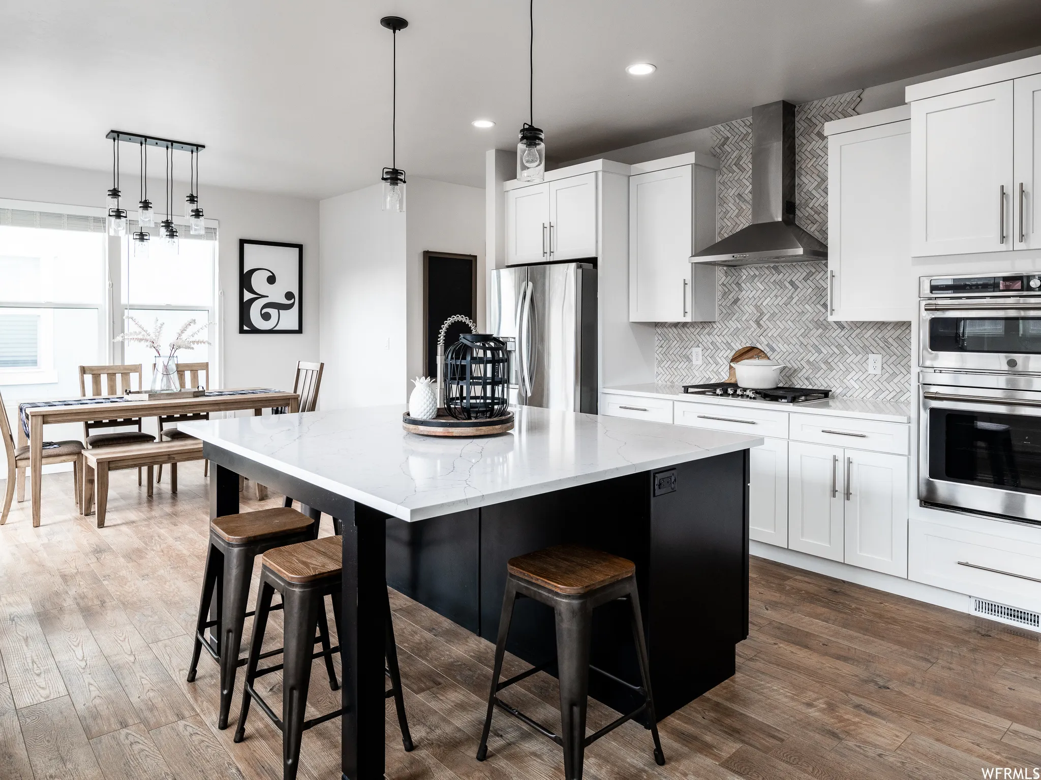Two tone kitchen featuring light stone countertops, stainless steel appliances, an island with sink, dual tone cabinetry, and a breakfast bar