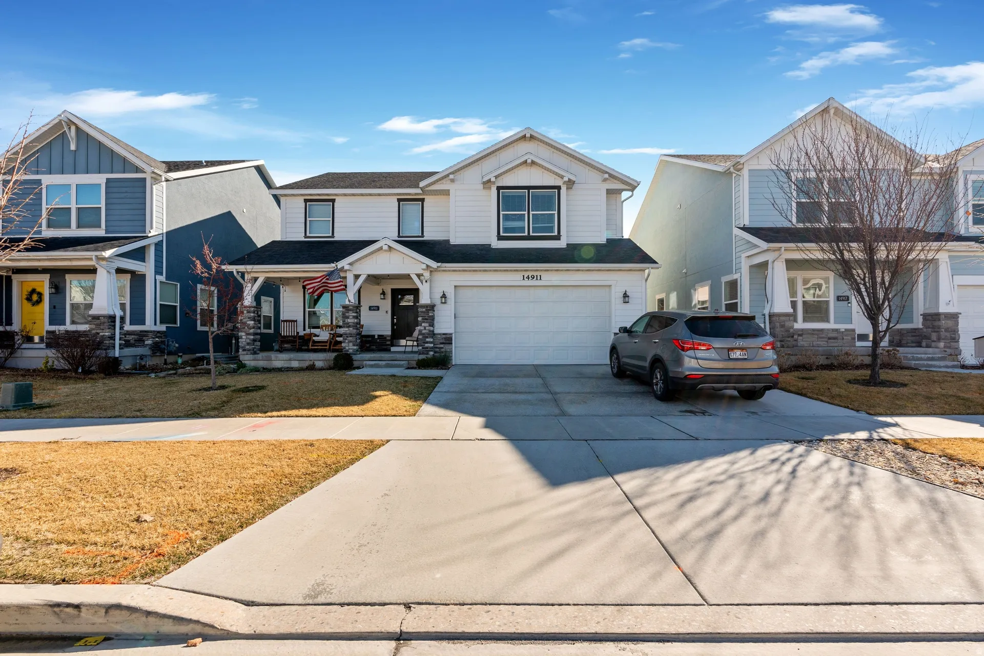 Craftsman house with covered porch, concrete driveway, an attached garage, stone siding, and a front yard
