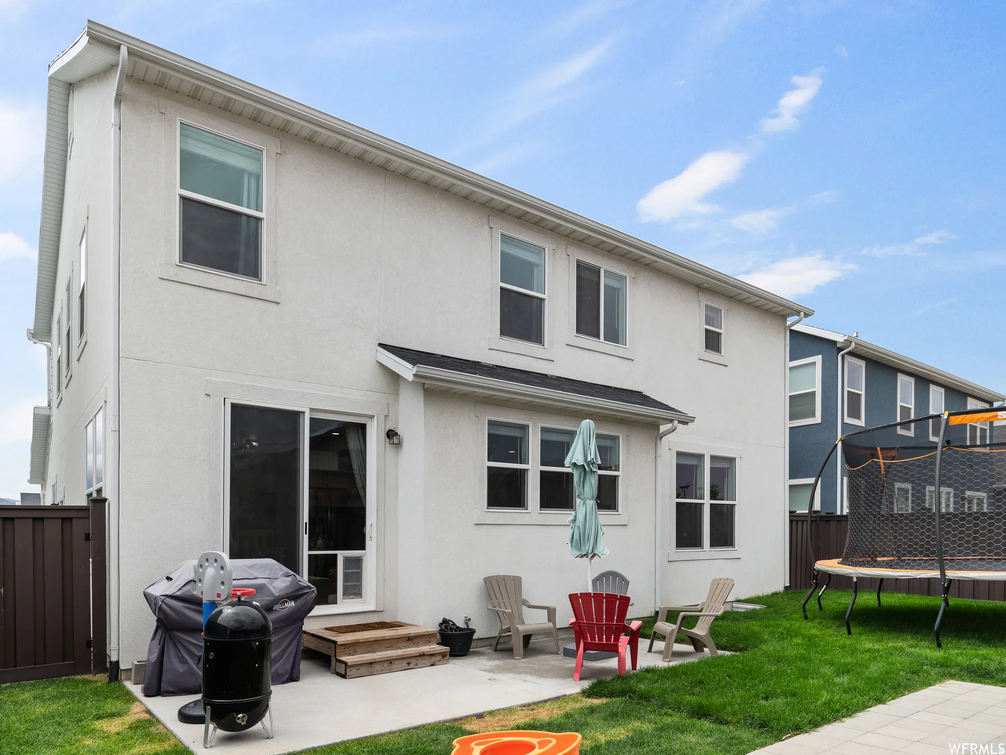 Back of property with a fenced backyard, a trampoline, stucco siding, and a patio area