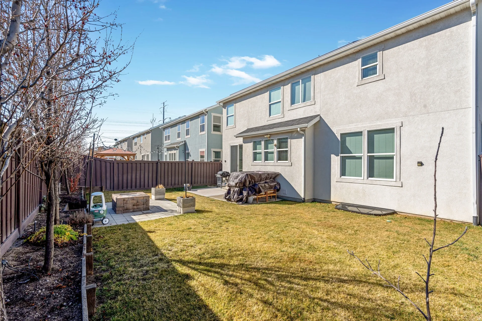 Back of house with stucco siding, a fire pit, a patio, and a fenced backyard
