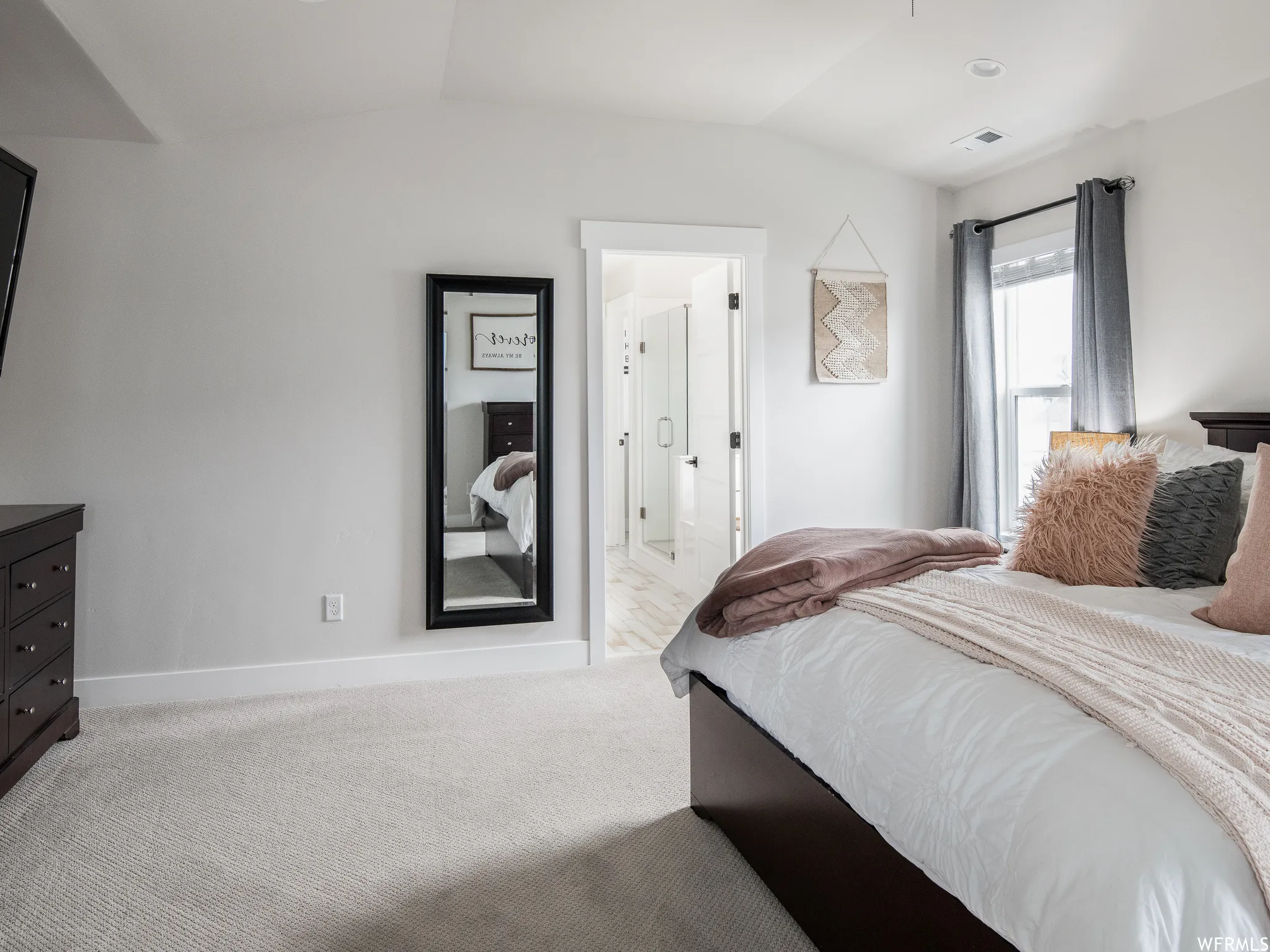 Bedroom with lofted ceiling, light carpet, and ensuite bath