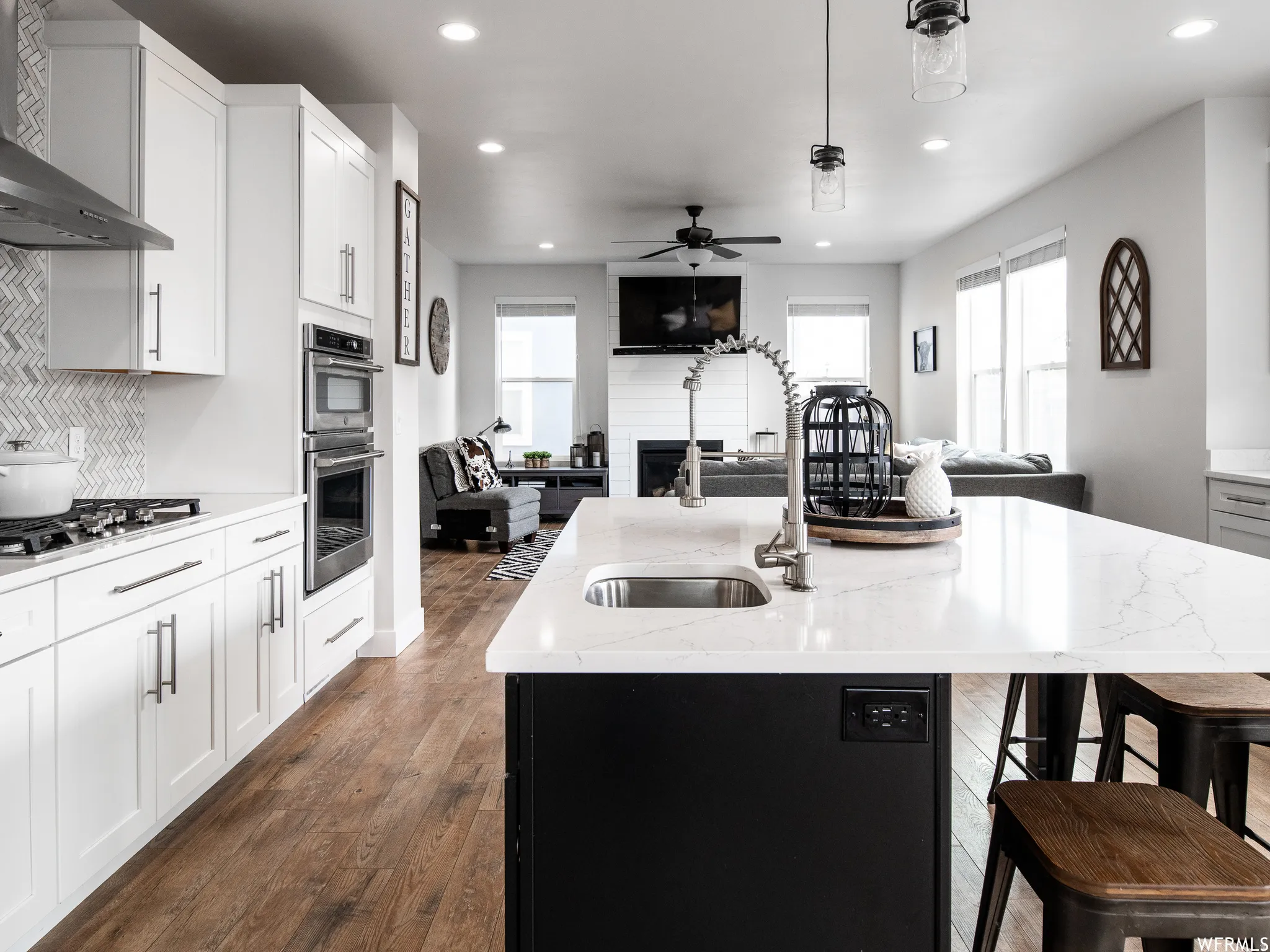 Kitchen with open floor plan, an island with sink, dark wood finished floors, a breakfast bar, and a large fireplace