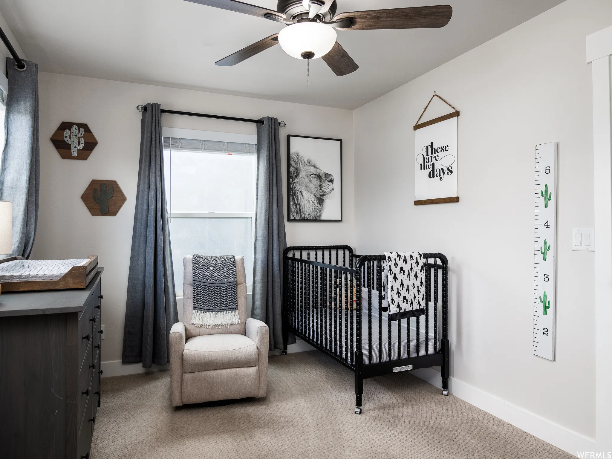 Bedroom with a nursery area, light colored carpet, and a ceiling fan