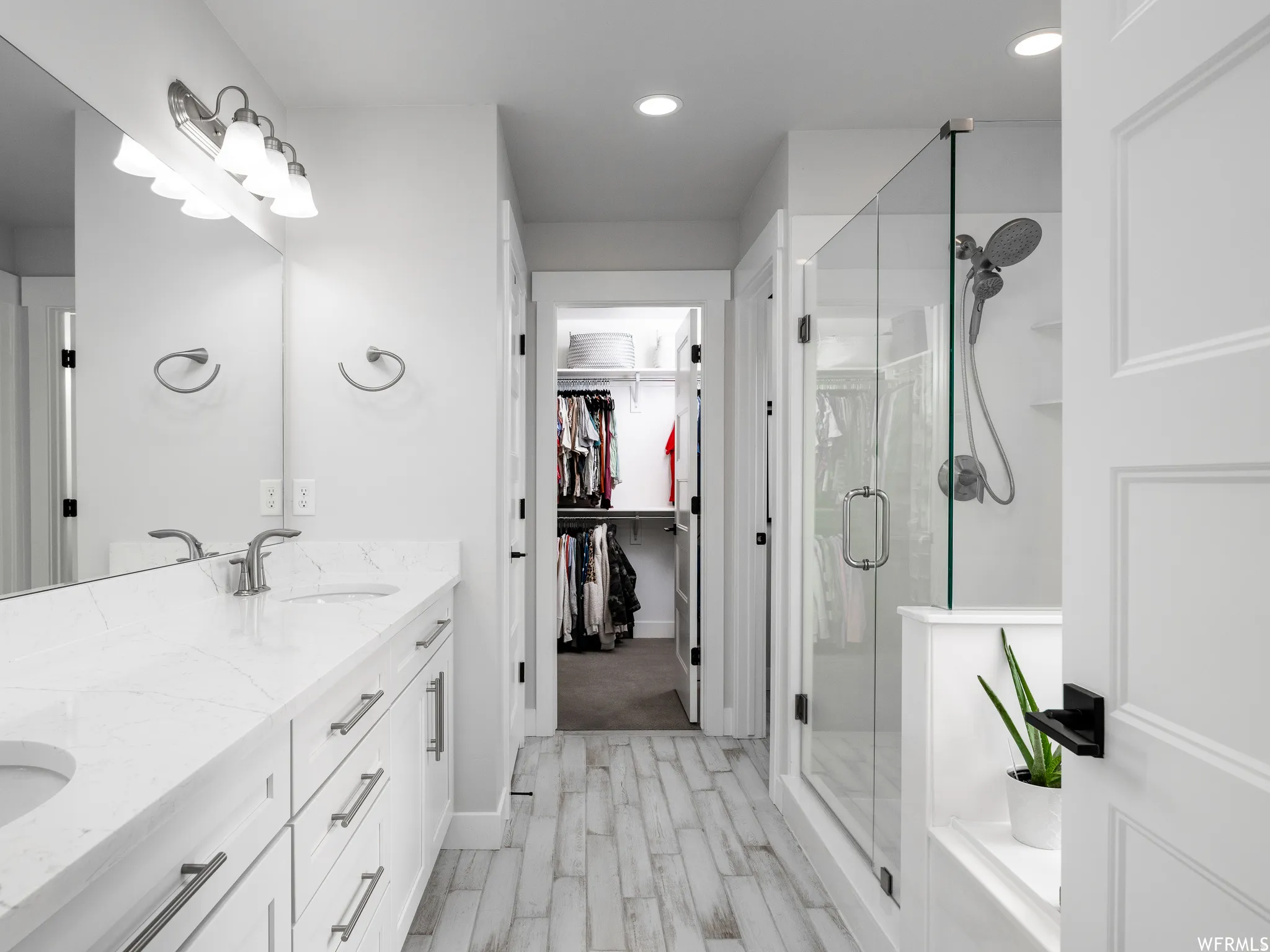 Full bathroom with a shower stall, double vanity, light wood-style floors, recessed lighting, and a walk in closet