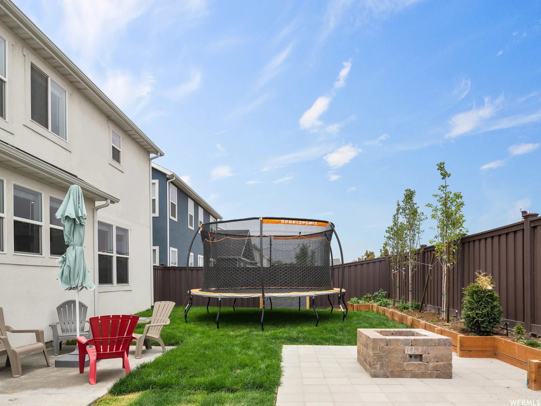Fenced backyard with a patio, a trampoline, and a fire pit