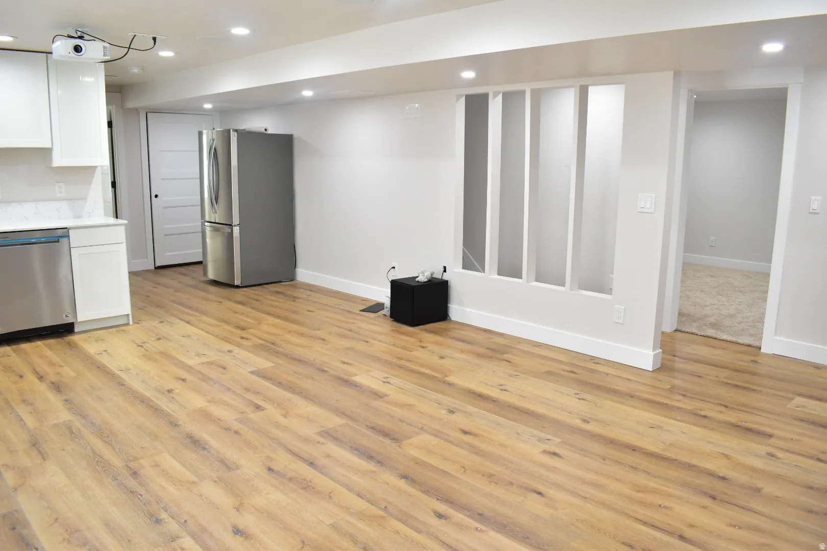 Kitchen featuring white cabinets, recessed lighting, stainless steel appliances, light wood-style flooring, and light stone counters