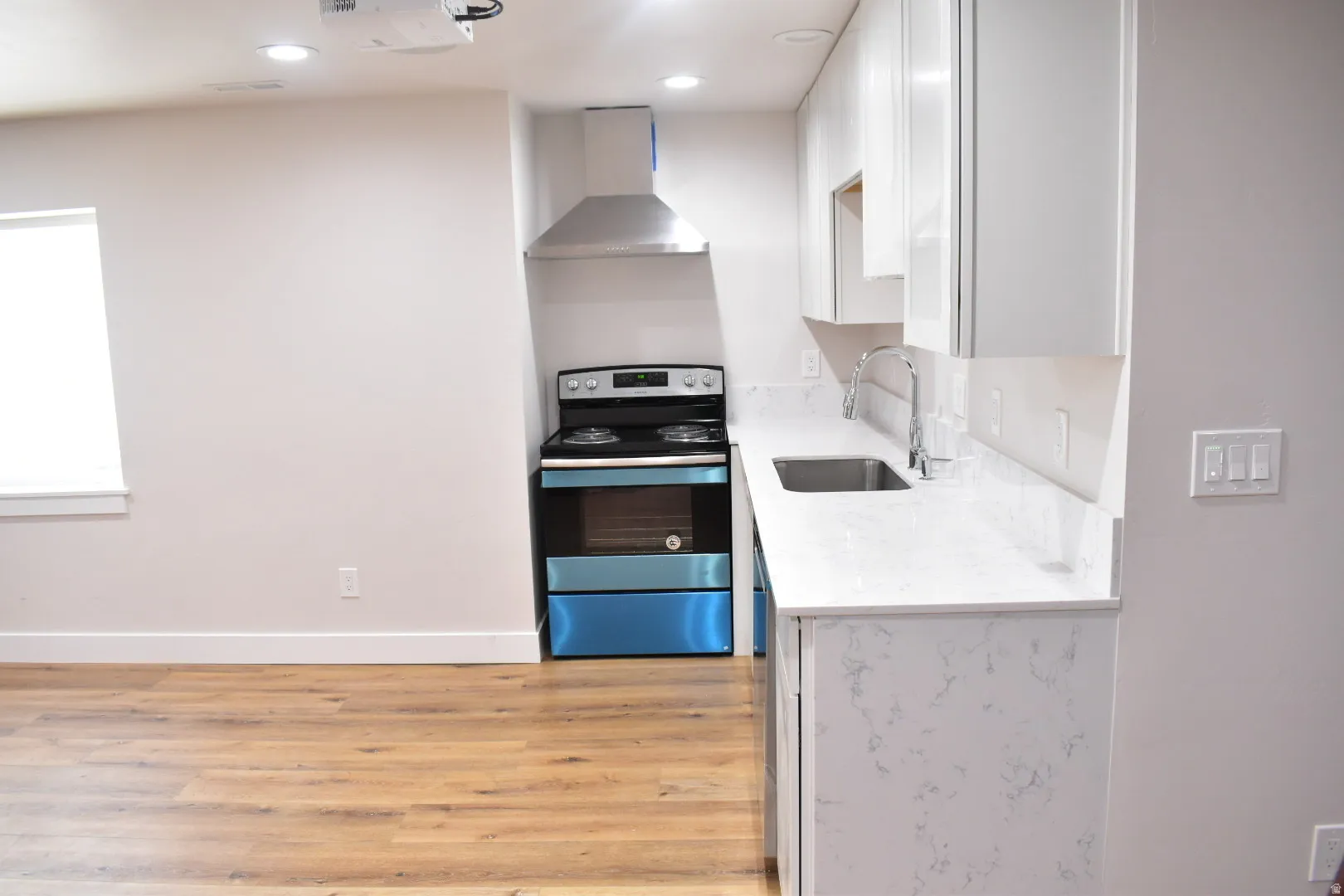 Kitchen with stainless steel electric range oven, light stone counters, white cabinetry, light wood-style floors, and recessed lighting