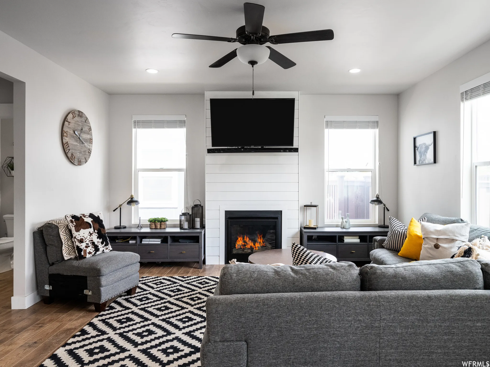 Living room with a large fireplace, ceiling fan, wood finished floors, and recessed lighting