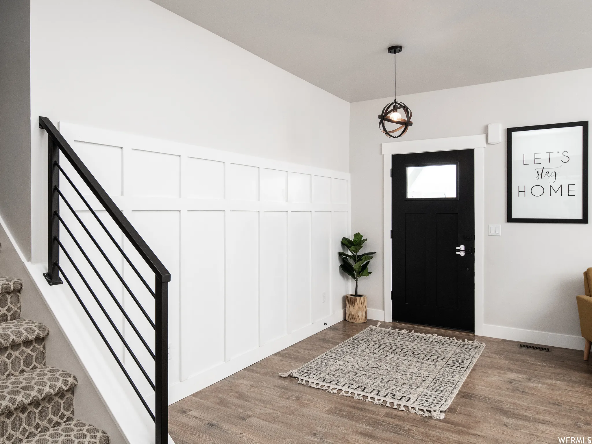 Entryway featuring a decorative wall, wood finished floors, and wainscoting