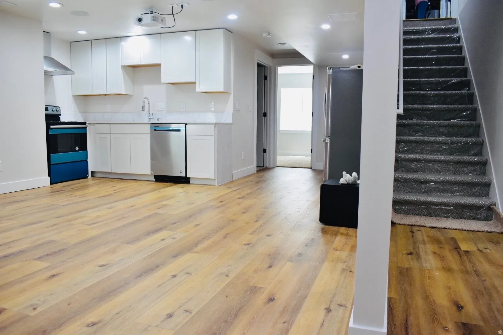 Kitchen featuring stainless steel appliances, white cabinets, light countertops, light wood-type flooring, and recessed lighting