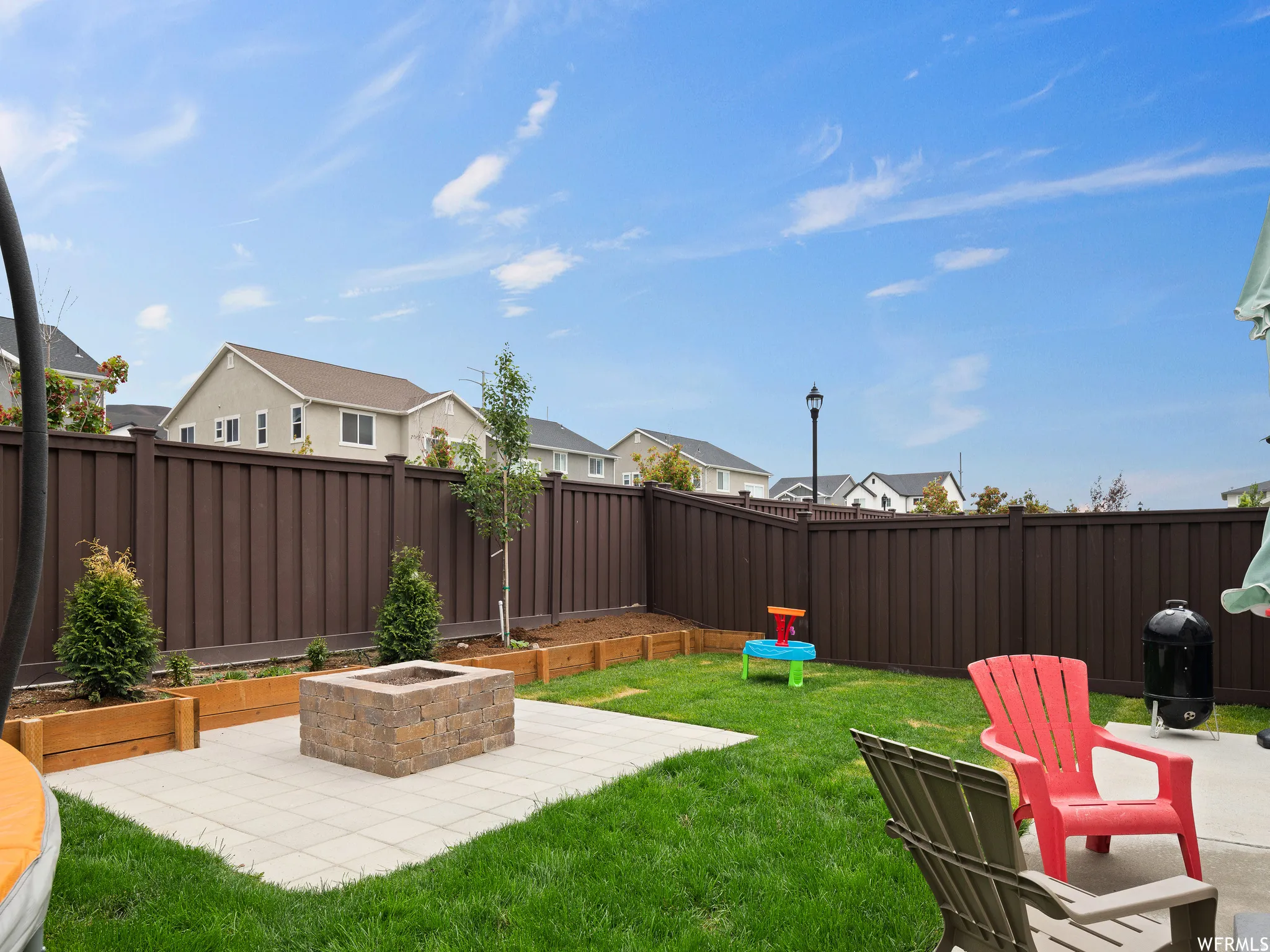 Fenced backyard with a patio, an outdoor fire pit, and a residential view