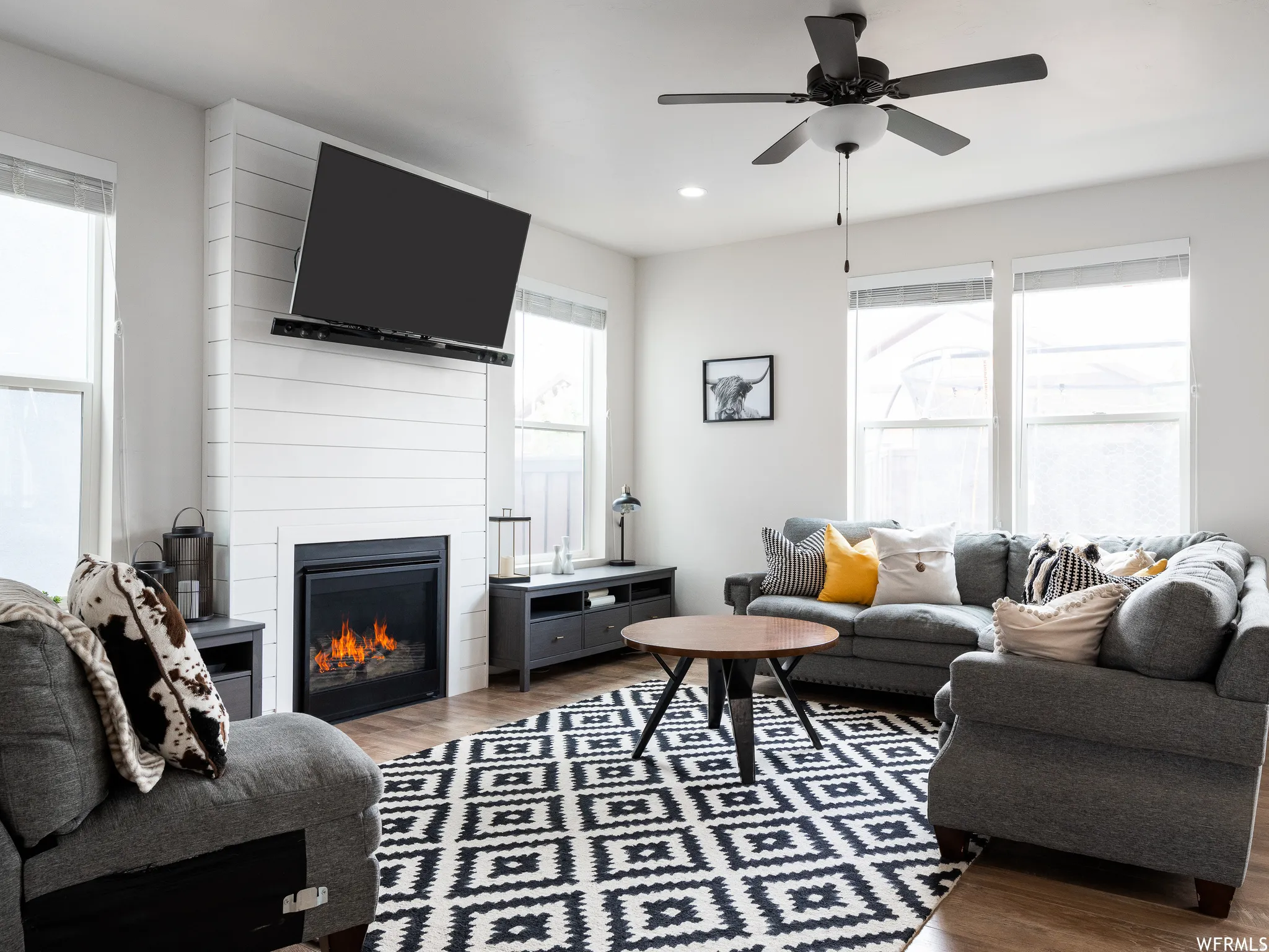 Living area featuring wood finished floors, a fireplace, ceiling fan, and recessed lighting